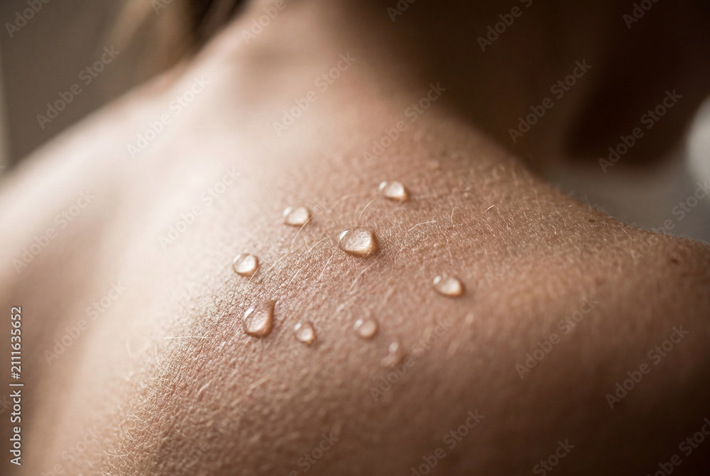 Fototapeta premium Clear water droplets resting on human shoulder skin after sweating