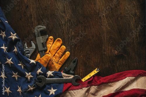 Work glove with tools and American flag on wood background. Symbolic of blue collar workers, USA manufacturing, pride in products Made in United States of America, or Father's day or US Labor Day.