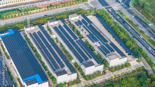 Obraz na płótnie Aerial shot of multiple industrial buildings with rooftop solar panel arrays, surrounded by roads and greenery