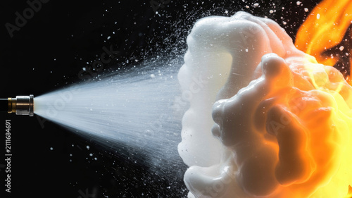 Pressurized white firefighting foam extinguishing intense orange flames against dark background with suppression