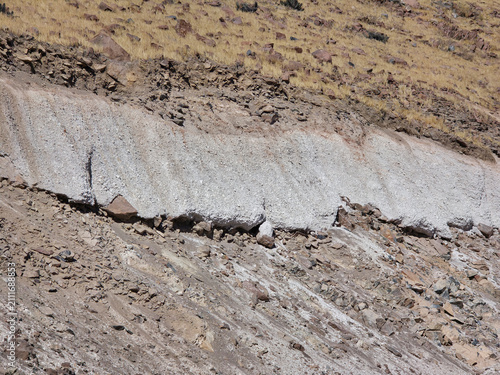 Horizontal white mineral vein exposed on a dry grass-covered hillside