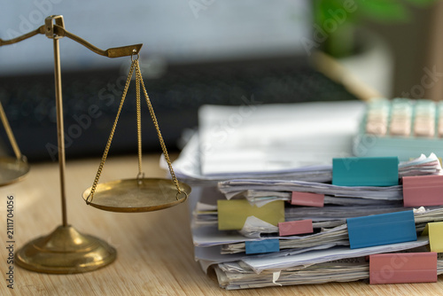 Obraz na plátně Golden scales sit beside stacks of papers with colorful tabs