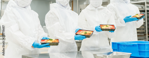 Obraz na plátně A man and a woman preparing bento boxes in a kitchen (food factory, food process