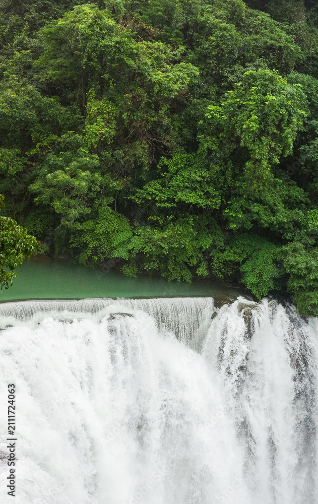 Fototapeta premium Majestic Shifen Waterfall in Pingxi District, New Taipei City. A popular natural tourist attraction in Taiwan featuring powerful cascading water and lush green foliage.