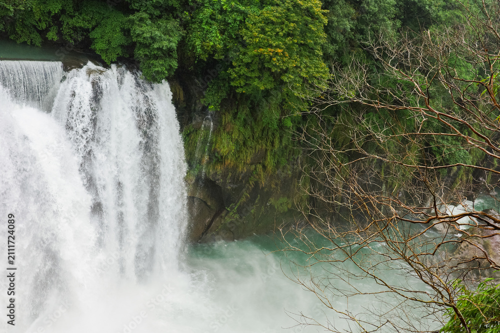 Fototapeta premium Majestic Shifen Waterfall in Pingxi District, New Taipei City. A popular natural tourist attraction in Taiwan featuring powerful cascading water and lush green foliage.