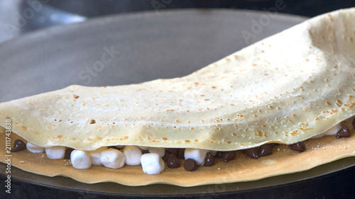 Close up on a french dessert crepe cooking filled with marshmallows and chocolate.