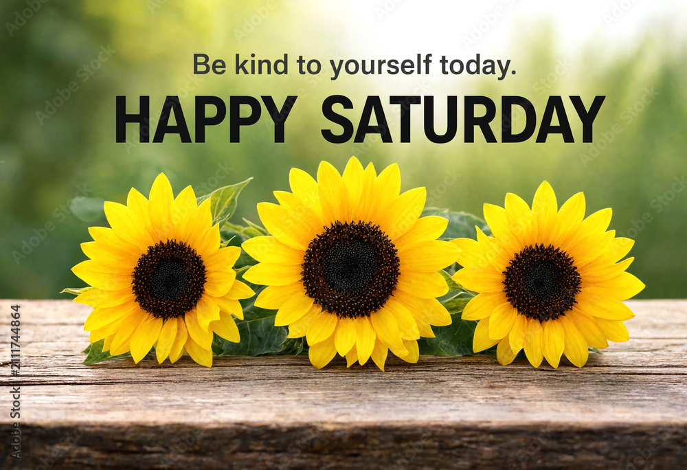 Obraz premium Bright yellow sunflowers on wooden surface with happy saturday motivational quote for positivity and selfcare