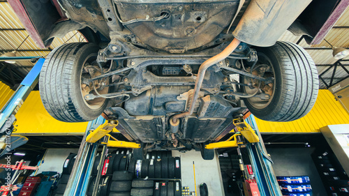Car suspension and undercarriage system maintenance in repair shop.