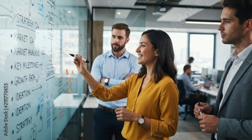 Business team brainstorming strategy and growth plans on a glass whiteboard