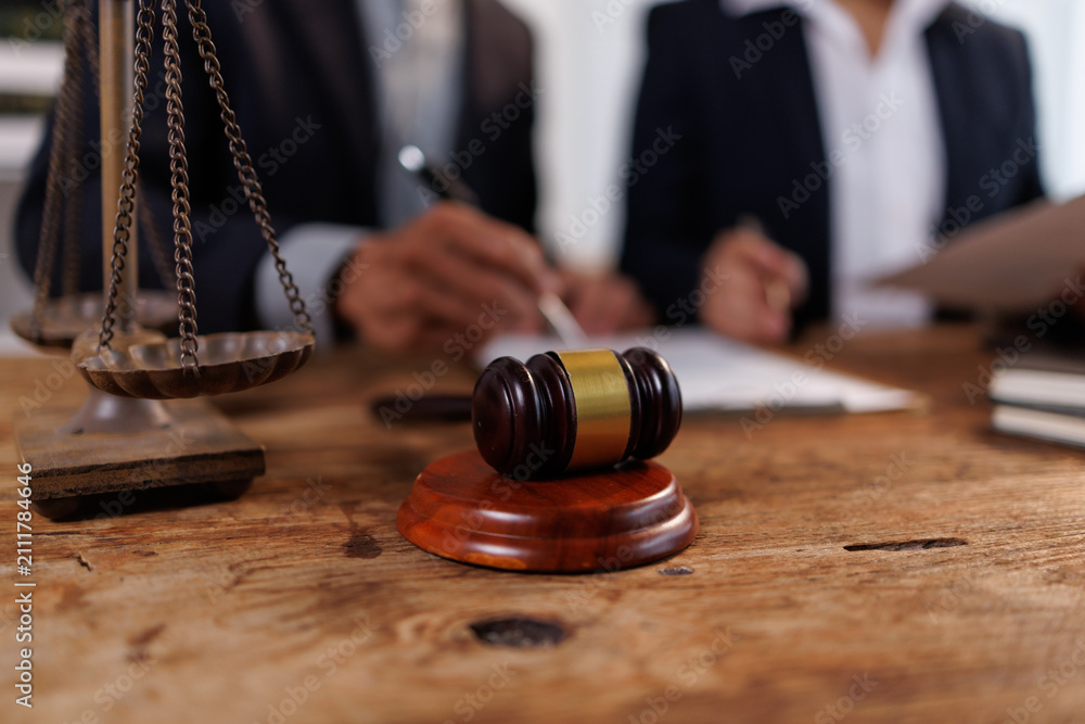 Obraz premium Lawyers engaging in a legal consultation, discussing contract documents with a gavel and scales of justice on the wooden table, symbolizing justice and law
