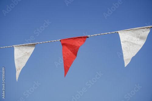 Red And White Pennant Bunting Flags Against Clear Blue Sky For Outdoor Party And Celebration