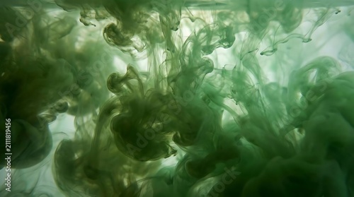 Green ink clouds dissolving in clear liquid abstract background