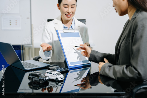 Asian people car salesman or sales manager offers to sell a car and explains of signing a car contract and signing car insurance document or lease paper.