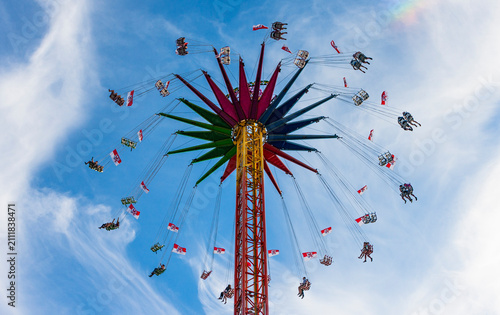 A tall chair swing ride with multiple riders enjoying the attraction. The amusement ride conveys motion, height, speed, and excitement at a fair, carnival, or amusement park.