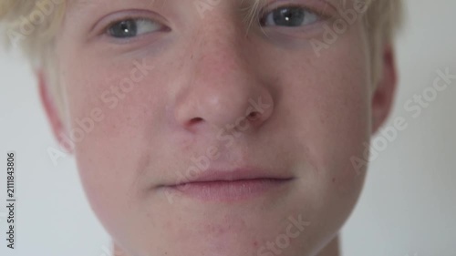 Close-up portrait of a smiling blond boy wearing dental braces against a light background