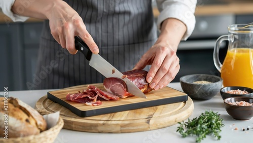 Chef cutting fresh red onion on a wooden board in the kitchen