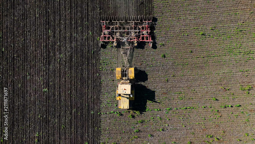 Принти на полотні Yellow tractor cultivating the land before planting, drone view