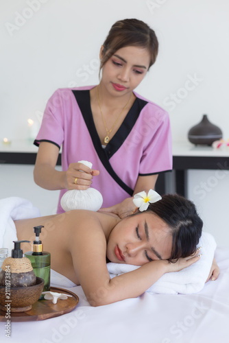 Asian woman enjoying a relaxing spa massage while lying on a massage table with eyes closed. Professional therapist providing wellness treatment in a luxury spa with massage oil,