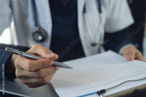 Cuadro en lienzo Close up of female doctor writing notes on clipboard, history record or healthca