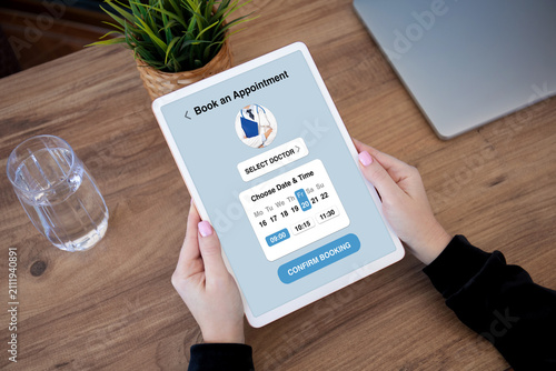 Woman holding tablet with medical doctor appointment booking app interface