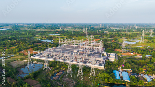 Foto An aerial view of a large electrical substation with transmission towers, set in a green rural area with water bodies and vegetation