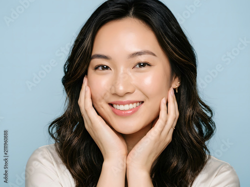 Smiling Asian woman touching her face. Portrait of a happy girl with healthy glowing skin.