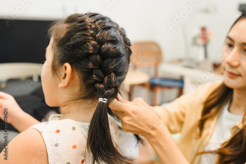 Canvas Print Woman braiding the hair of a young girl indoors at home