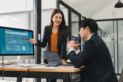 Canvas Print Asian businesswoman presenting data on a computer screen to a colleague in an of