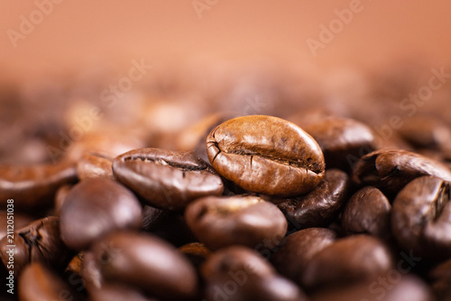 Close-up of roasted coffee beans and a coffee pod on a brown background