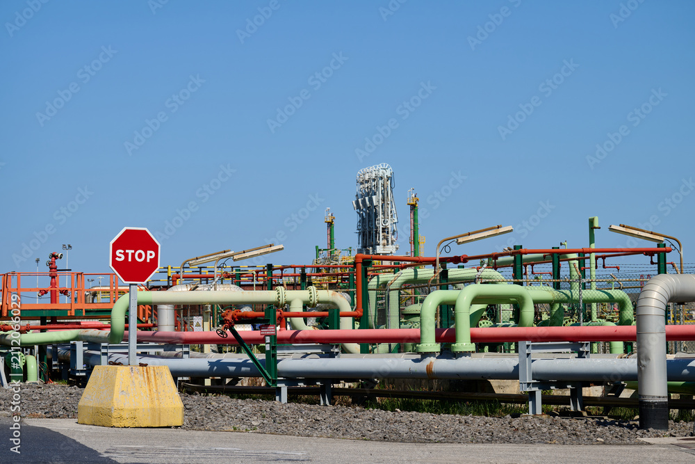 Naklejka premium Stop sign standing before industrial pipeline infrastructure