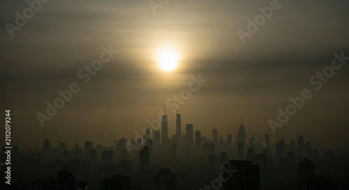 Panoramic view of a modern urban skyline silhouette under a hazy sunset light during a dusty golden hour atmosphere