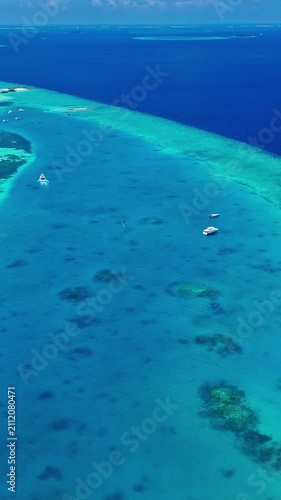A serene aerial view of the tranquil tropical reef in the Maldives, showcasing clear blue water and sandy beaches under a sunny holiday atmosphere. This high-altitude perspective offers.