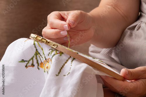 the hands of woman are busy with embroidery