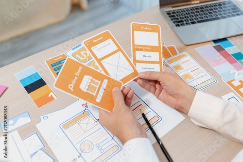 Obraz na płótnie Designer arranging wireframes, interface components, and color palettes to develop UX and UI concepts, supporting product design, user experience planning, and digital application development