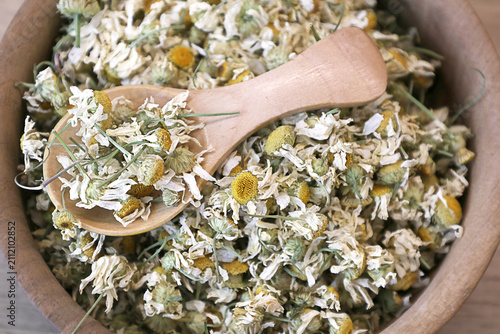 Canvastavla Close-up of dried chamomile flowers in a wooden bowl with a wooden spoon