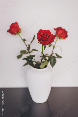Fotografía Beautiful red roses in an elegant white vase bring warmth to a simple setting