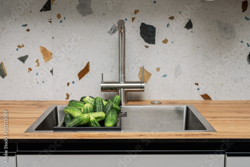 Foto Fresh homegrown cucumbers in a modern kitchen sink before washing and food preparation