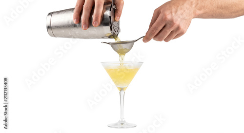 Photography Bartender straining a yellow cocktail into a martini glass with a fine mesh siev