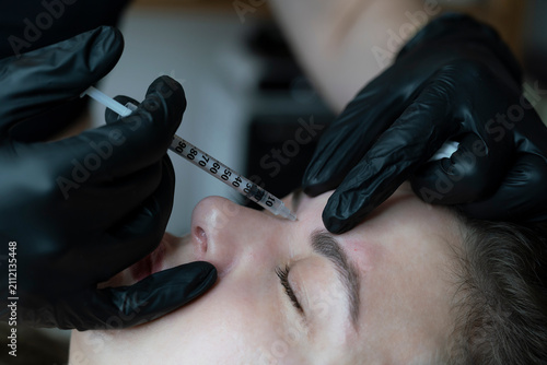 Foto woman lies in an armchair, receiving a cosmetic injection, a close-up of a rejuv