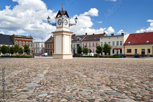 Fotografie A cobblestone market square surrounded by tenement houses with a clock tower in