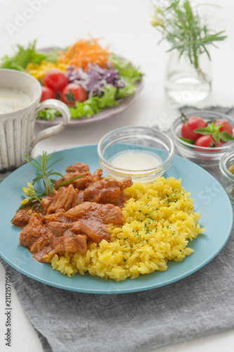 青いプレートに盛り付けられたバターチキンカレーと彩り野菜のランチセット