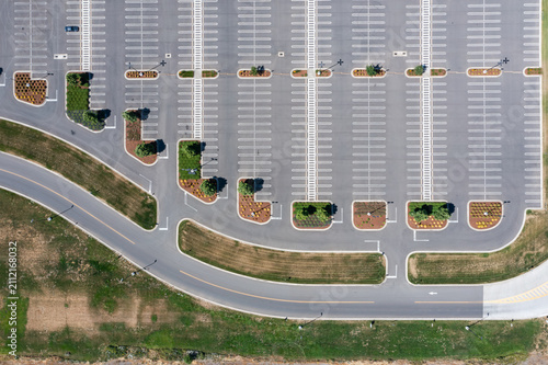 Aerial drone photo of a large commercial parking lot with parked cars beside an industrial warehouse and distribution facility in Woodburn, Oregon, USA on a clear summer day