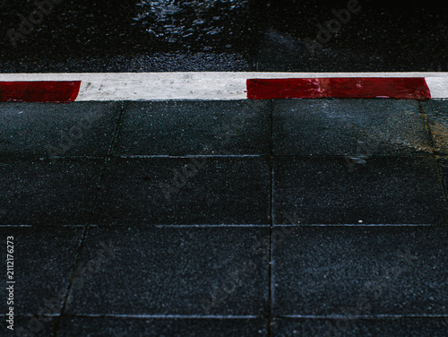 Curb Detail with Red Marking Reflecting Wet Pavement Under Overpass in Rain