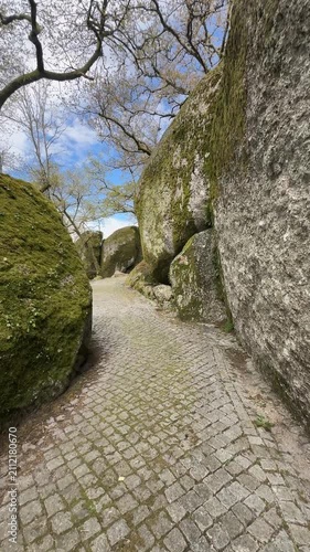 Rocky cobblestone pathway winding between massive moss covered granite boulders in Penha Guimarães