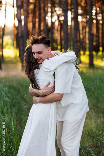 Foto Young couple embracing tenderly in a sunlit forest during a wedding ceremony