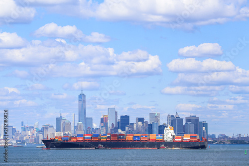 Container ship passes Lower Manhattan with One World Trade Center in New York City, USA.