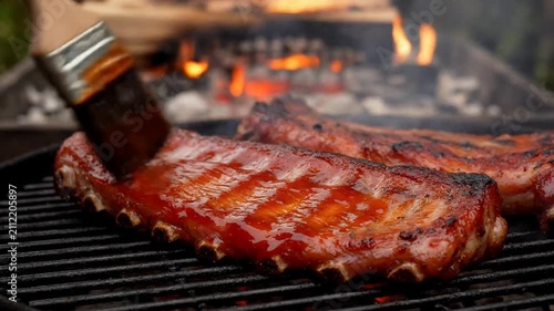 Pork ribs grilling on barbecue grill with flames in background