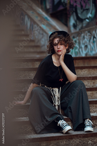 Картината върху платно Young Woman Sitting on Graffiti Covered Stairs
