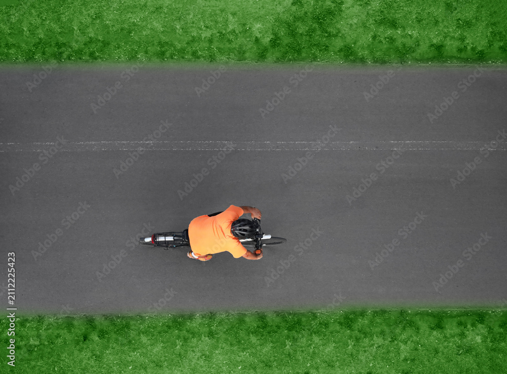 Fototapeta premium Aerial top drone high view of sporty male Cyclist with helmet shorts riding cross bicycle on black asphalt road background backdrop Top view showing man on racing bicycle riding Motion