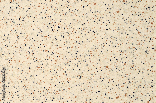 Macro close up of a light beige terrazzo stone texture with brown and dark blue speckles